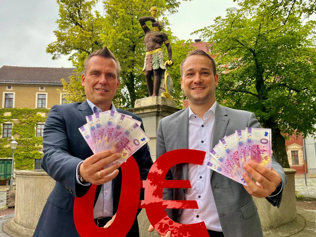 Bürgermeister Michael Kieslich (links) und Sparkassen-Filialleiter Matthias Thiele präsentieren den  0-Euro-Schein zum Stadtrechtsjubiläum.
